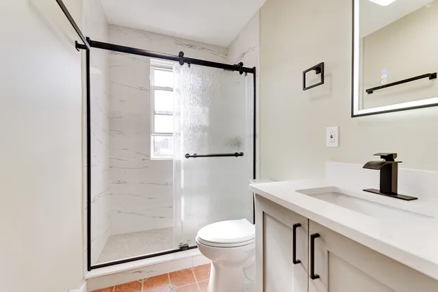 a bathroom with a granite countertop sink toilet and shower