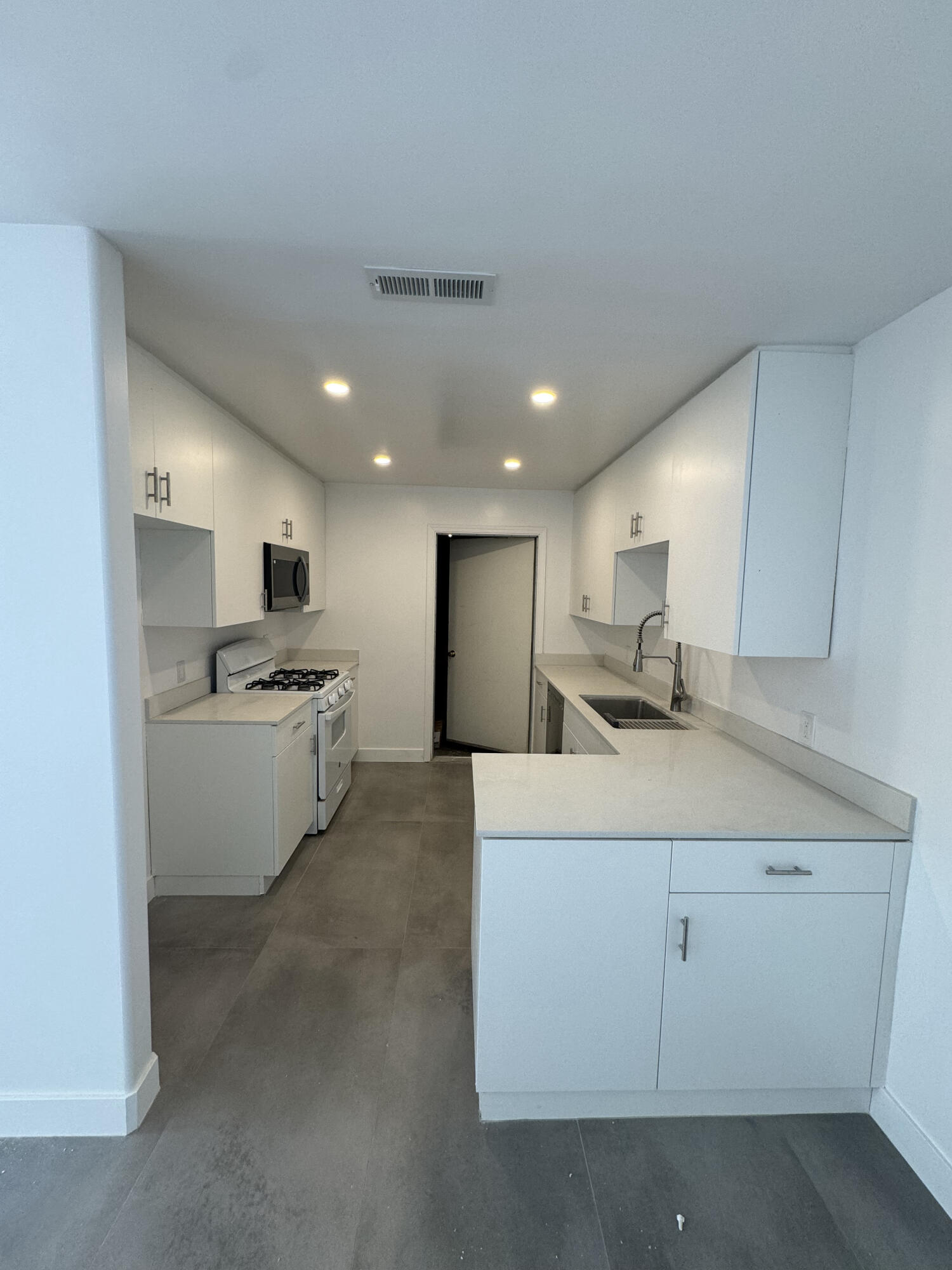 a large white kitchen with a stove a sink a refrigerator and a oven