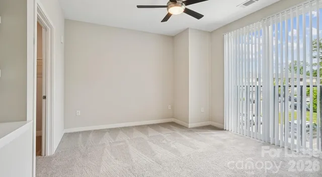 an empty room with a ceiling fan and carpet
