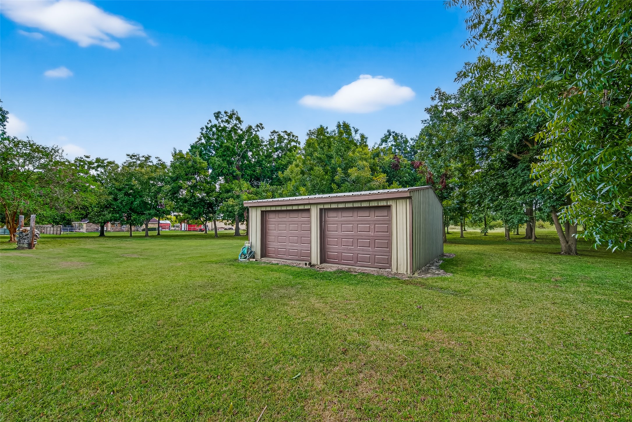 12021 7th 1/2 Street Santa Fe, TX 77510 - Photo 13 of 49 This photo shows a spacious backyard featuring a workshop for enthusiast or side business, surrounded by lush green grass and mature trees, providing a serene and private setting.