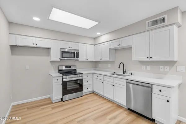a view of an empty room with wooden floor and a bathroom