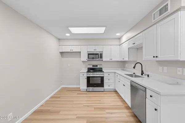 a kitchen with granite countertop white cabinets stainless steel appliances and sink