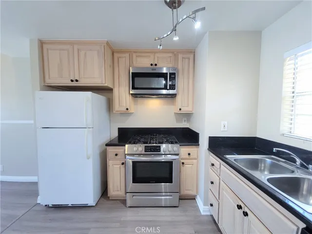 a kitchen with granite countertop a sink a stove and refrigerator