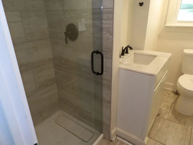 a bathroom with a granite countertop sink a toilet and shower