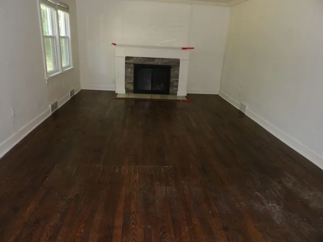 a view of empty room with wooden floor and fireplace