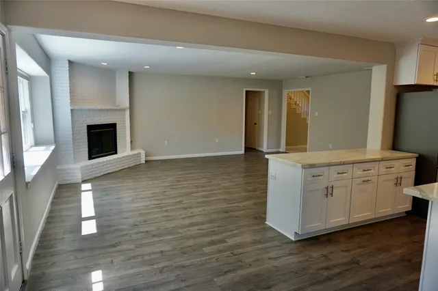 an empty room with wooden floor fireplace and windows