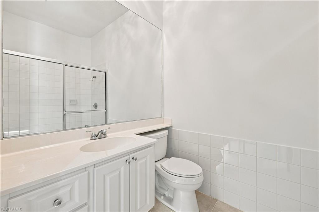 4470 Novato Court Naples, FL 34109 - Photo 12 of 33 White vanity with recessed paneling and chrome hardware, a white undermount sink, and a light-colored countertop
