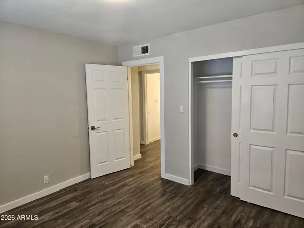 a view of an empty room with wooden floor and closet area