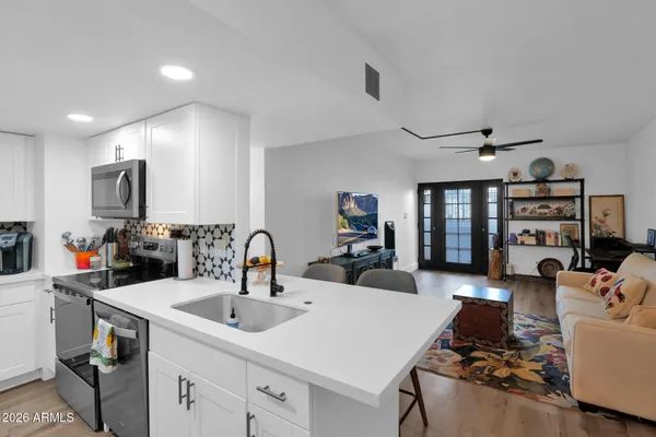 a kitchen with a sink dishwasher a stove and a dining table with wooden floor