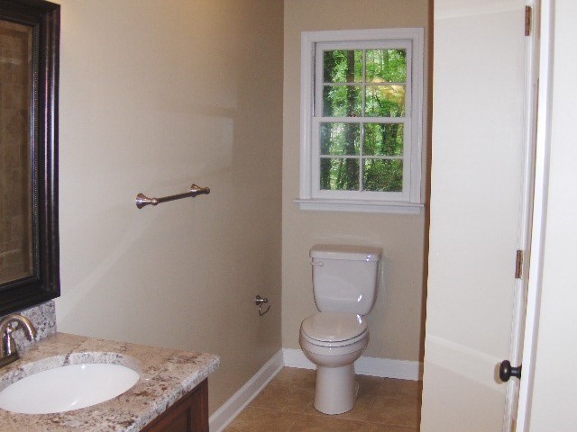4660 Arkwright Road Macon, GA 31210 - Photo 19 of 32 a bathroom with a granite countertop toilet a sink and a window