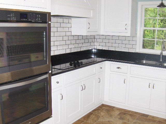 4660 Arkwright Road Macon, GA 31210 - Photo 7 of 32 a kitchen with granite countertop white cabinets and black appliances