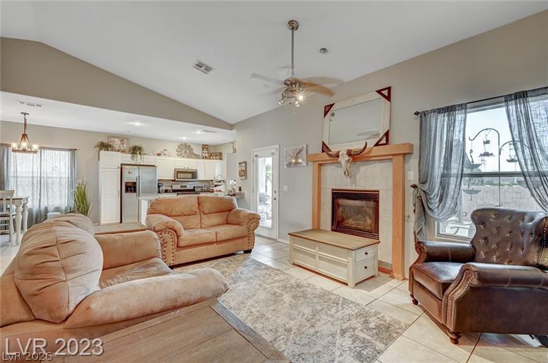 987 Cutter Street Henderson, NV 89011 - Photo 4 of 17 A spacious living area seamlessly connects to the kitchen, featuring a fireplace and vaulted ceilings.