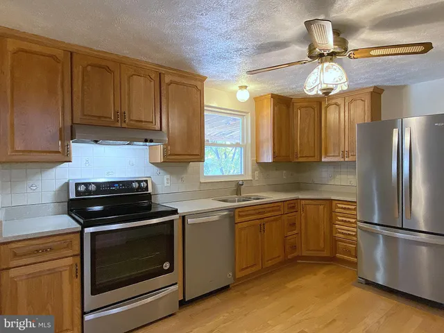 an empty room with wooden floor closet and windows