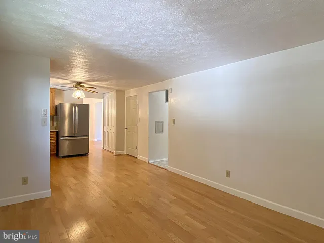 an empty room with wooden floor chandelier and windows