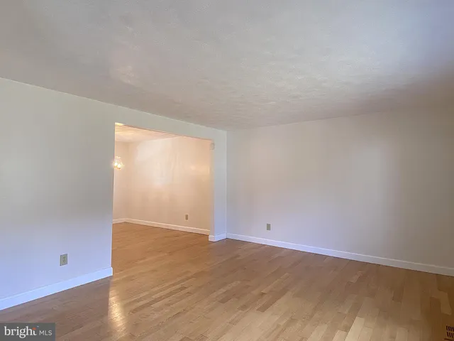 an empty room with wooden floor ceiling fan and window