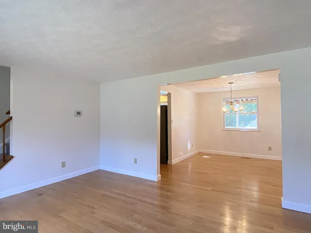 a view of a room with wooden floor chandelier and windows