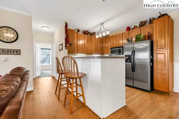 a kitchen with stainless steel appliances granite countertop a refrigerator a stove and a dining table with wooden floor