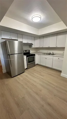 a kitchen with a refrigerator and a stove top oven
