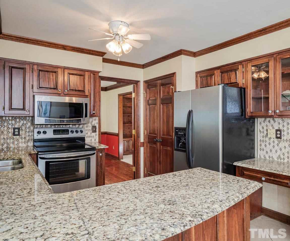 7100 Kinross Drive Raleigh, NC 27613 - Photo 5 of 24 a kitchen with stainless steel appliances granite countertop a refrigerator a stove and a sink