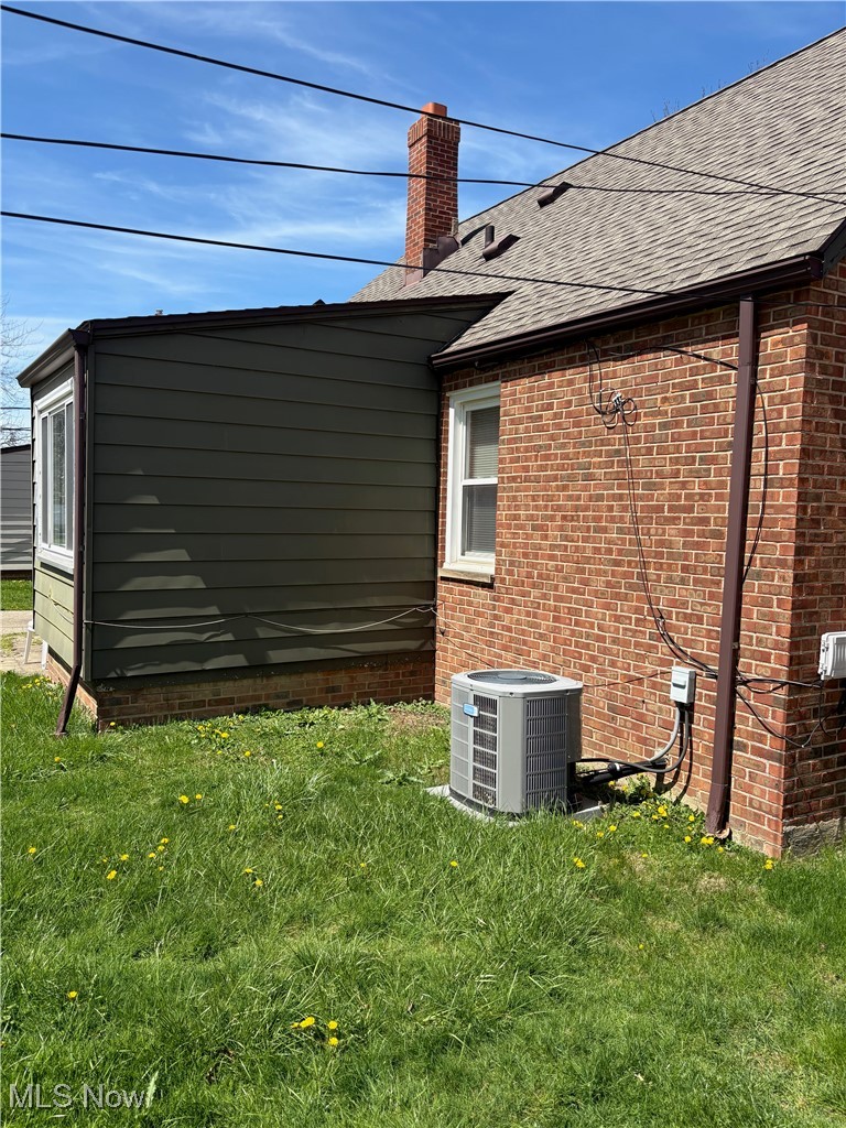 4218 Eastway Road Cleveland, OH 44121 - Photo 24 of 29 View of side of property with a lawn, a chimney, brick siding, and roof with shingles