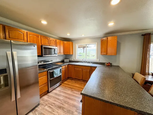 a large kitchen with stainless steel appliances granite countertop a sink a stove and a refrigerator