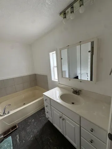 a bathroom with a tub sink and mirror