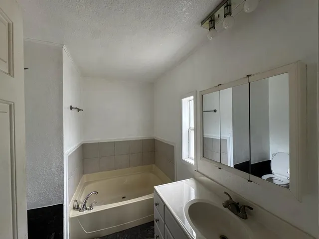a bathroom with a tub sink and mirror