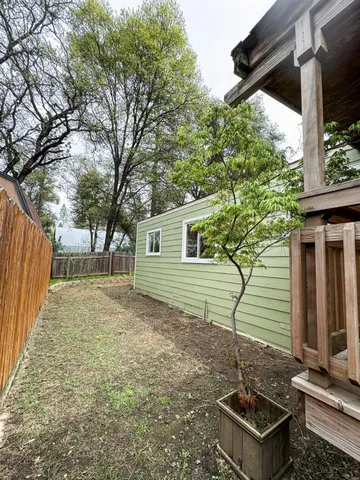 a backyard of a house with table and chairs a barbeque with wooden fence and floor