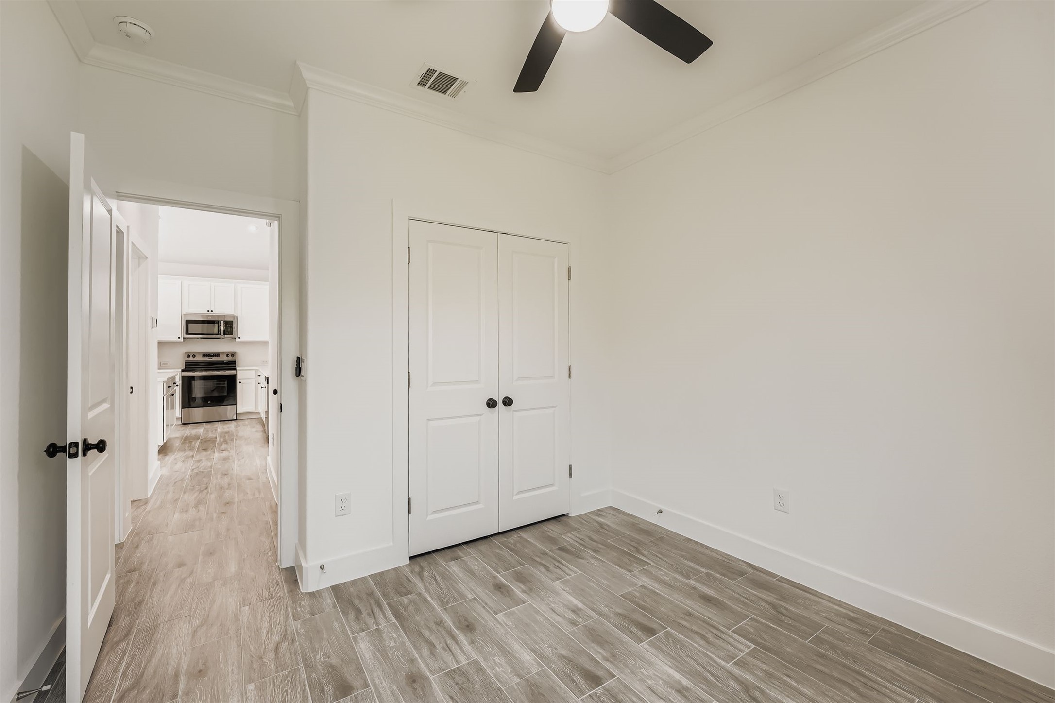 701 East 3rd Street Elgin, TX 78621 - Photo 22 of 35 Bedroom 2 featuring wood-style vinyl plank flooring, a closet and a view into the bright kitchen area