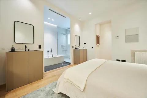 a spacious bedroom with a bed a mirror and vanity