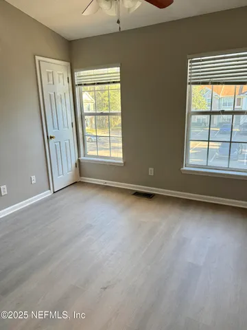 an empty room with wooden floor and windows