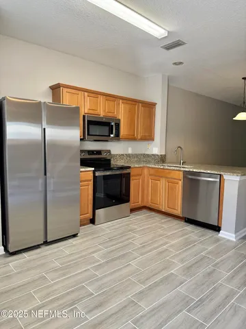 a kitchen with stainless steel appliances granite countertop a refrigerator and a sink