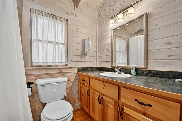 a bathroom with a granite countertop toilet a sink and a window