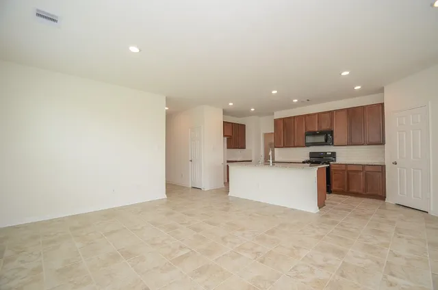 a kitchen with stainless steel appliances granite countertop a sink a stove and a wooden cabinets