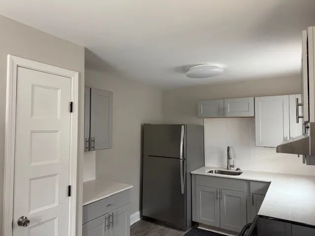 a kitchen with a refrigerator a stove top oven and cabinets
