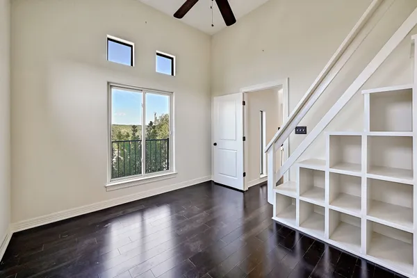 a view of an empty room with wooden floor and window