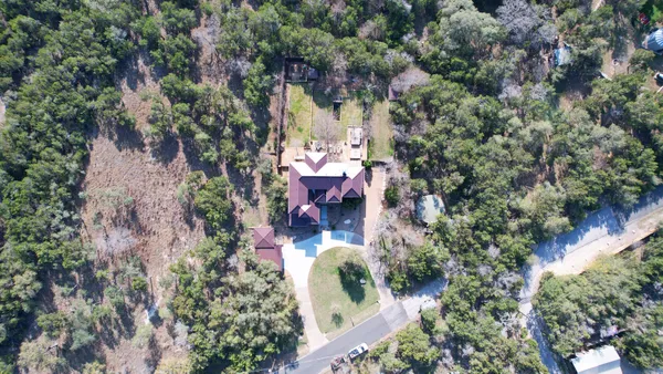 an aerial view of a house with a yard and large trees