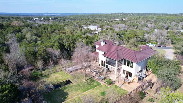 an aerial view of residential houses with outdoor space and trees