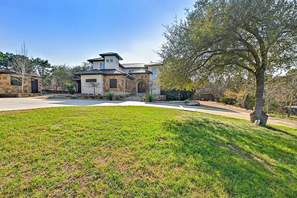 a view of a house with a big yard and large trees