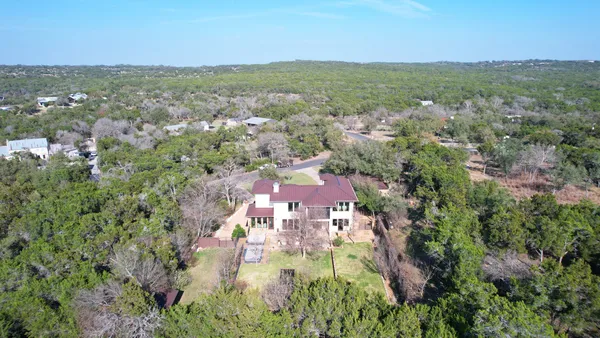 an aerial view of residential houses with outdoor space and trees