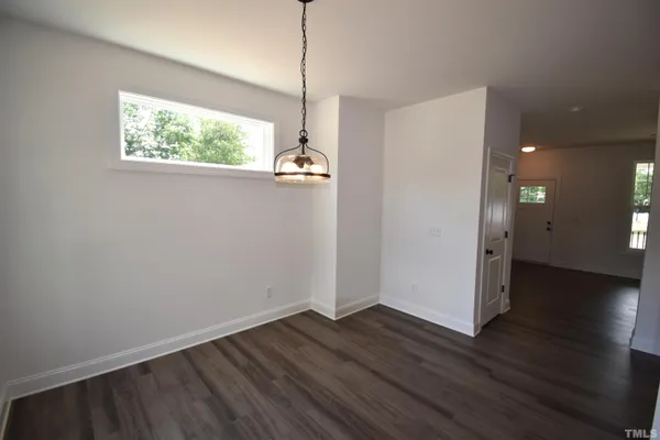 an empty room with wooden floor cabinet and windows