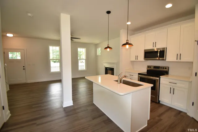 a kitchen with stainless steel appliances granite countertop a sink a stove and a wooden floors