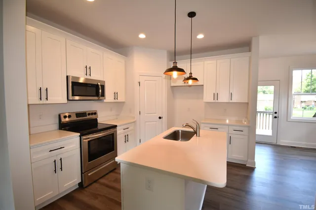 a kitchen with a sink a stove a microwave and wooden floor