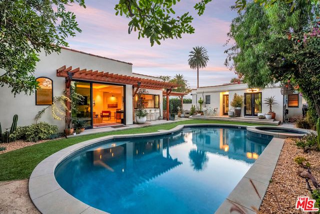 a view of a house with pool lawn chairs and a yard