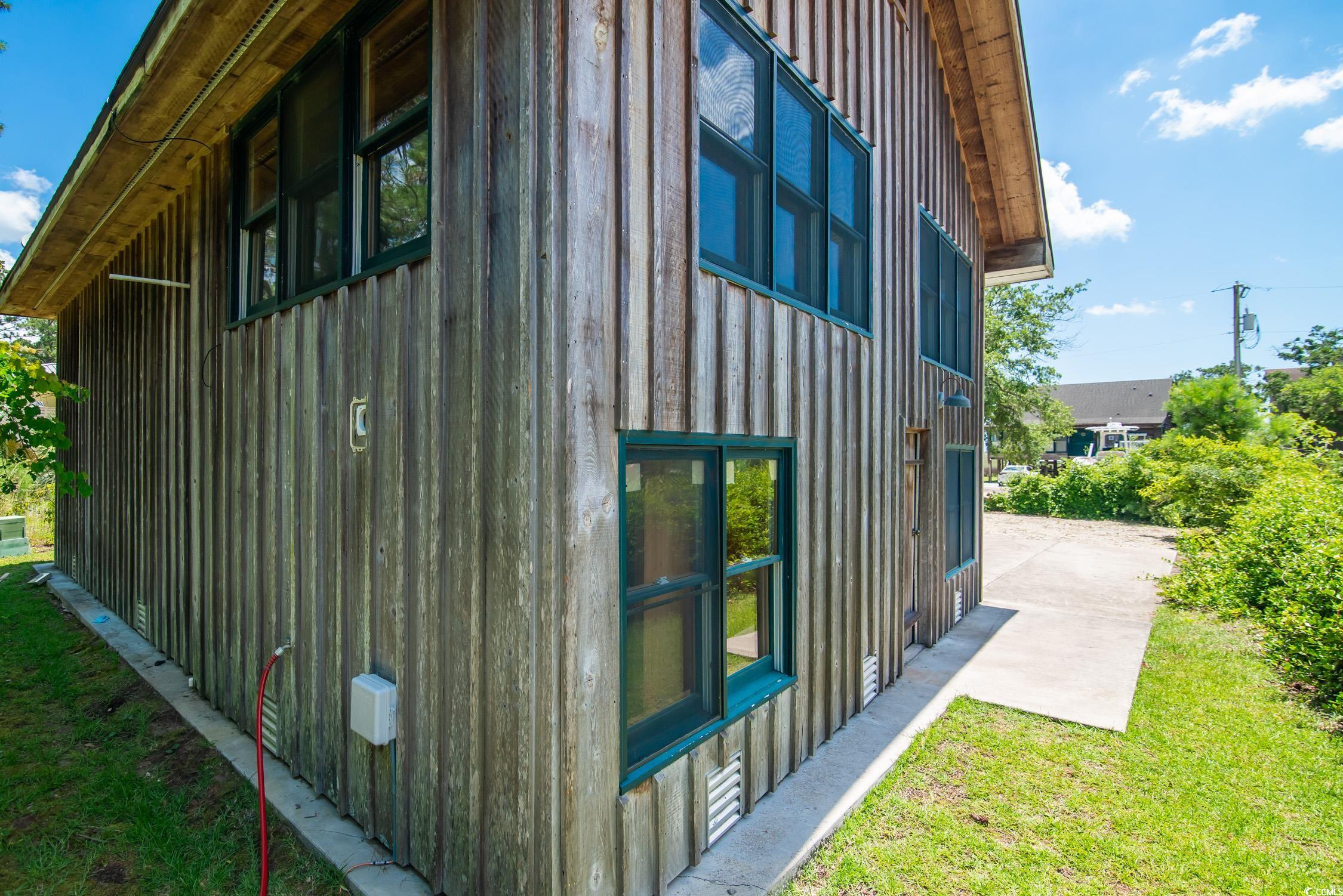 127 Brown Pelican Loop Pawleys Island, SC 29585 - Photo 5 of 31 View of side of property with board and batten siding, a patio, and a lawn