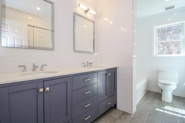 a bathroom with a granite countertop sink mirror and toilet
