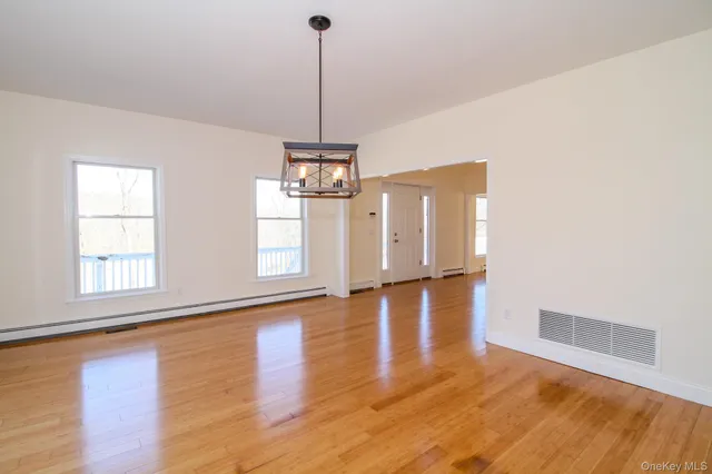 a view of empty room with wooden floor and window
