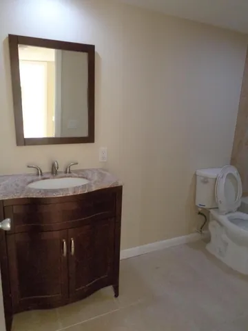 a bathroom with a granite countertop sink a mirror and a toilet