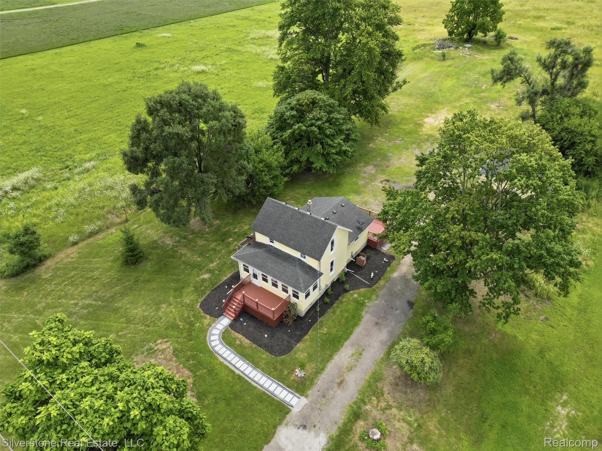 9691 Grames Road Maybee, MI 48159 - Photo 8 of 44 Two-story residence with a dark shingle roof, light-colored siding, and a red-toned deck