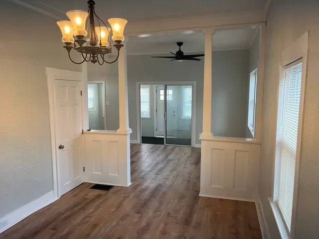 a view of a hallway with wooden floor and chandelier